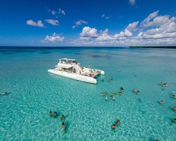 Catamarã parado na piscina natural da Ilha Saona, com turistas na água rasa